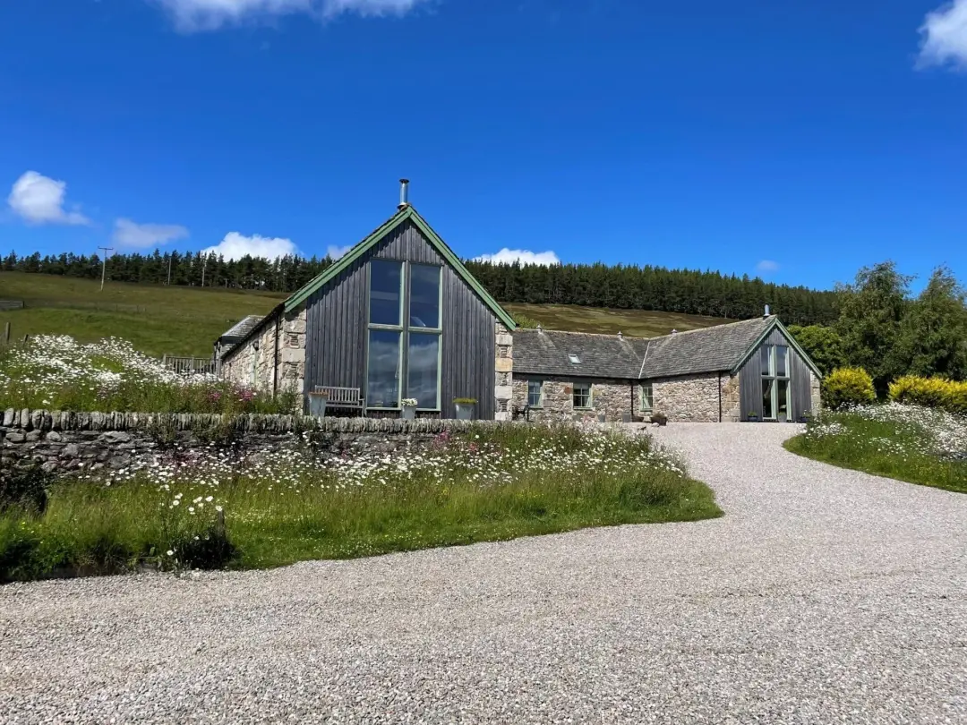 The stone and timber cottages at Balneden Steading behind a bank of white wildflowers