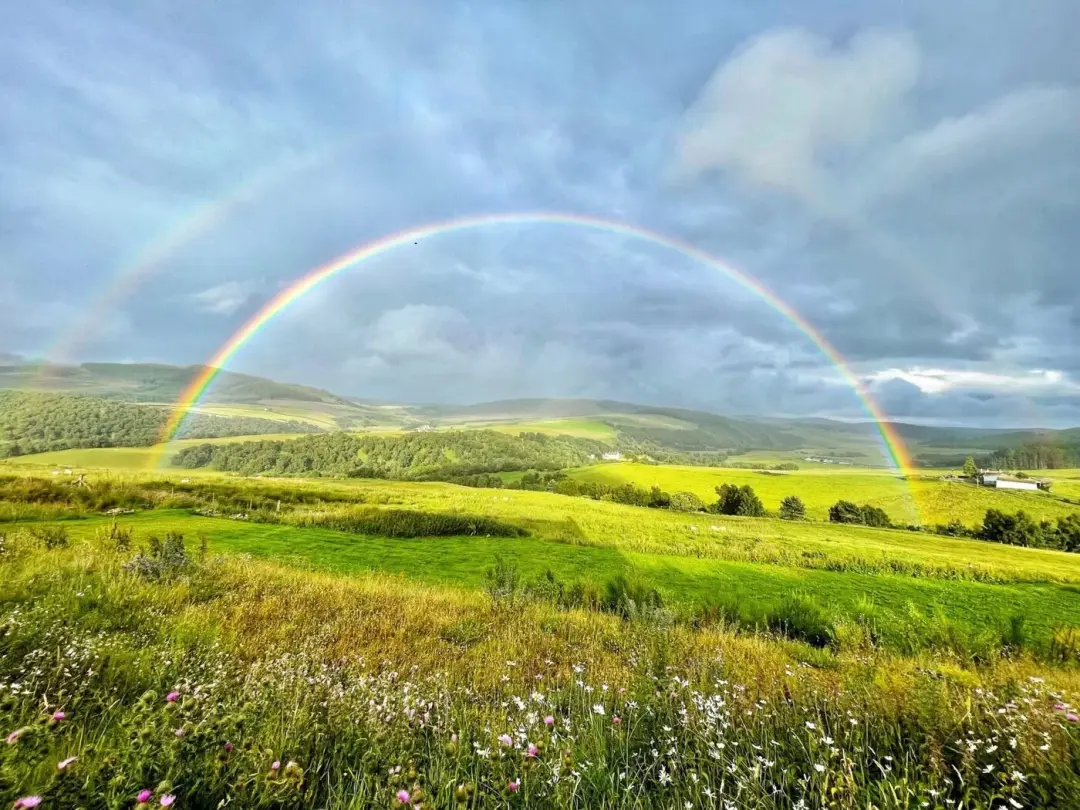 A rainbow over green fields and the hills of the Glenlivet Estate