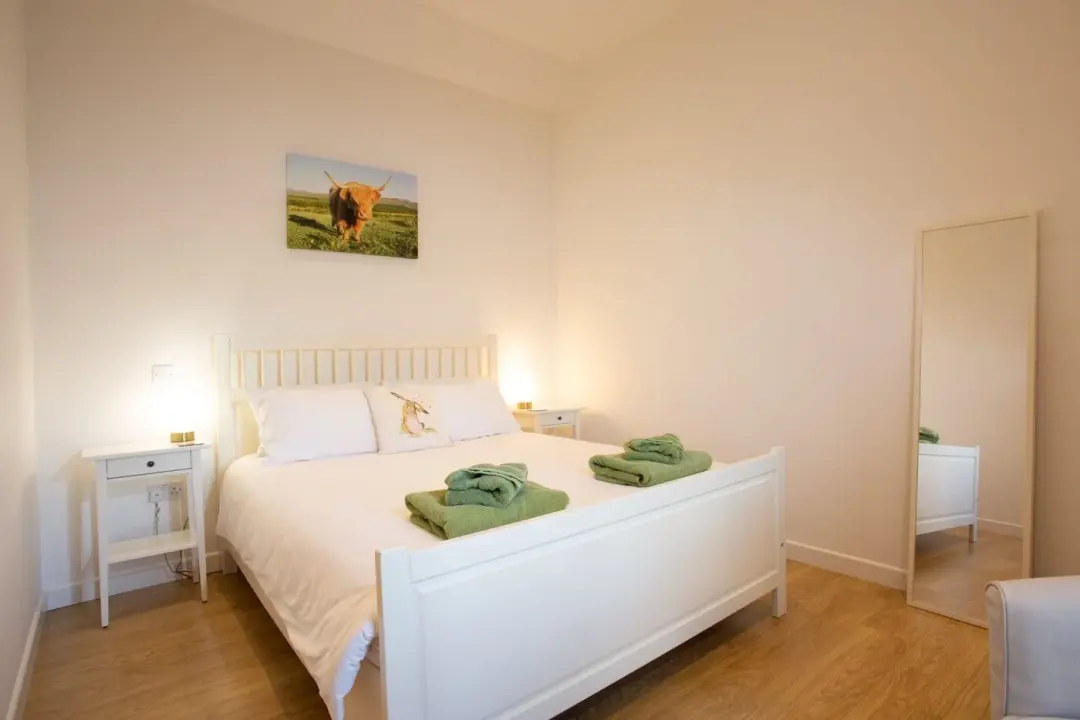 Bedroom at The Cattle Shed with a white king-size bed and folded green towels