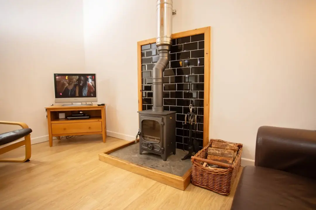 Wood-burning stove on a slate hearth beside the lounge at The Cattle Shed