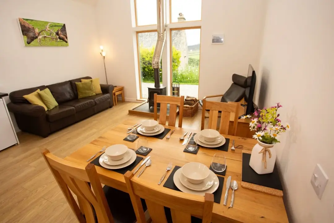 Dining table set for four beside the lounge and tall window at The Grain Store
