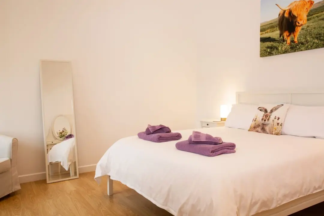 Double bedroom at The Grain Store with a king-size bed, purple cushions and a full-length mirror
