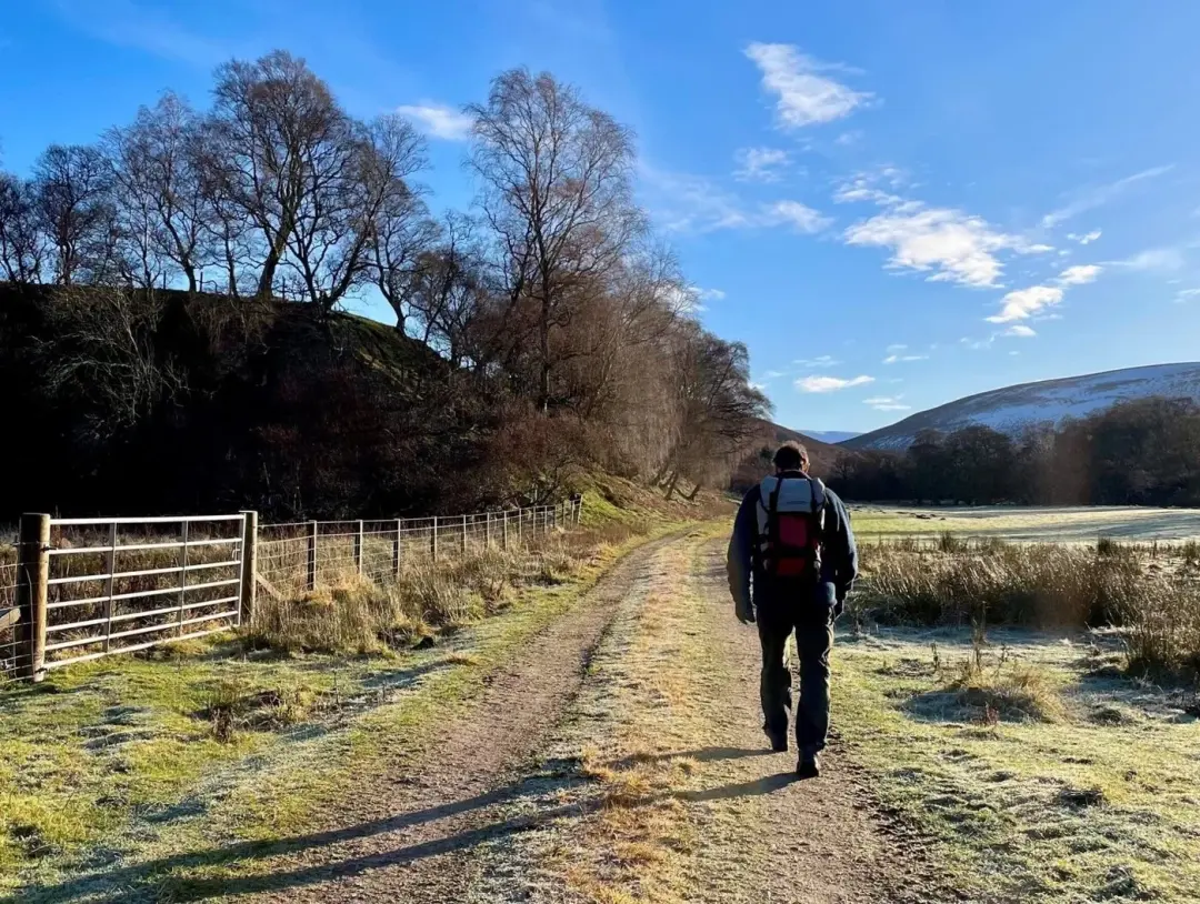 Walker on a frosty track with bare trees and snowy hills, on the Bochel circuit near Balneden
